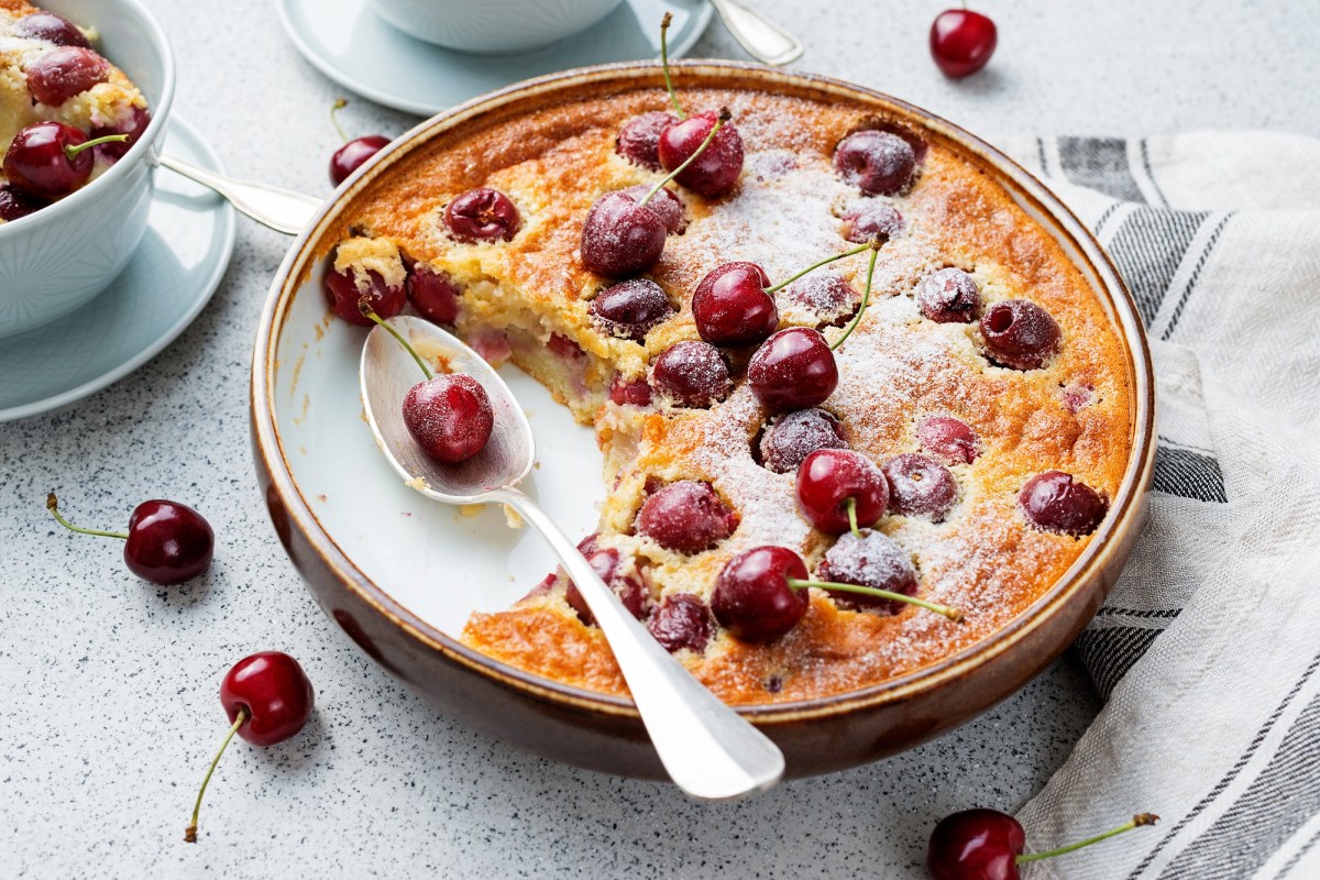 Clafoutis mit Kirschen in runder Form, in der schon eine Portion fehlt.