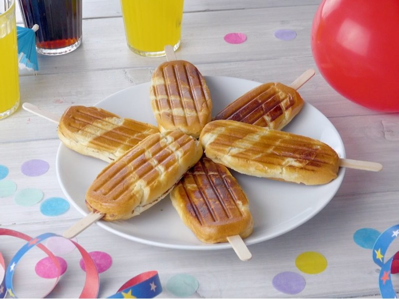 6 Milchbrötchen am Stiel, die sternförmig auf einem Teller liegen. Daneben stehen Gläser mit Limonade, Partydekorationen und ein roter Luftballon.