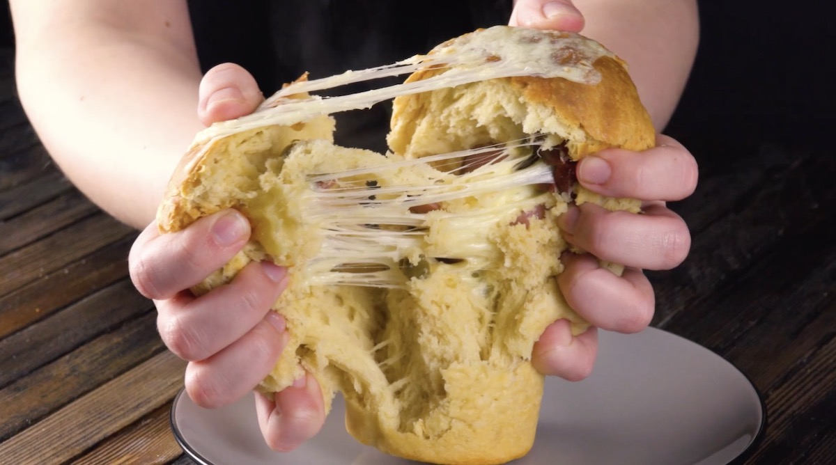 Ein Käse-Wurst-Brot wird auseinander gezogen.