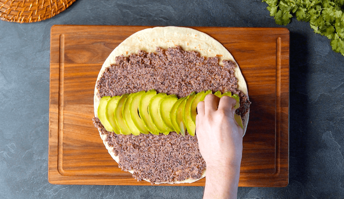 Avocadoscheiben werden auf einer Tortilla verteilt