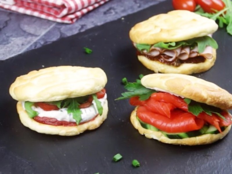 verschieden belegte Eiweiß-Brötchen auf einem Blech.