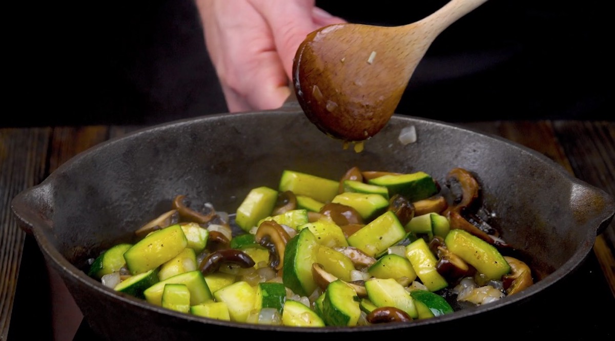 Klein geschnittene Zucchini und Pilze werden in Pfanne angebraten