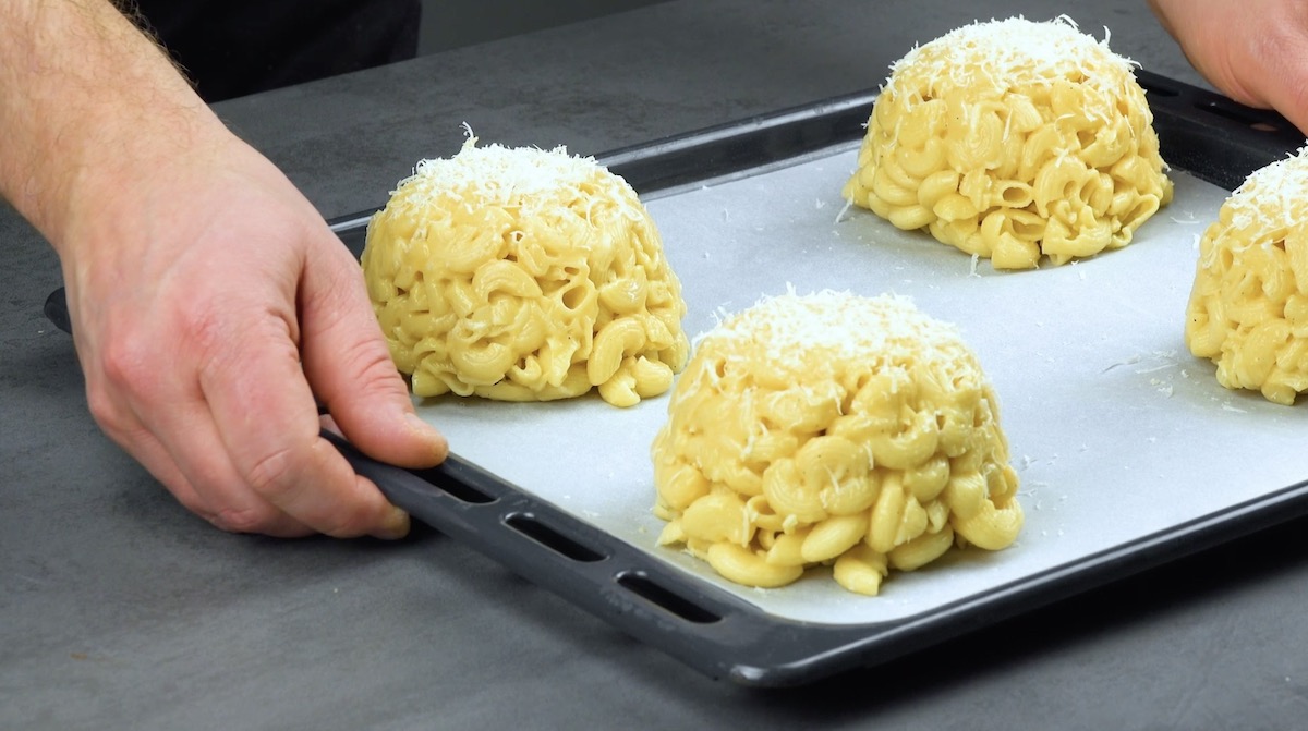 Die Hackfleisch-KÃ¤se-Nudeln in Kuppelform werden auf einem Backblech platziert und mit Parmesan bestreut.