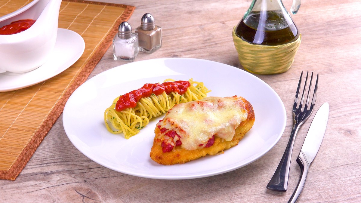 Parmesan-Hähnchen mit Nudeln und Tomatensoße auf einem Teller.