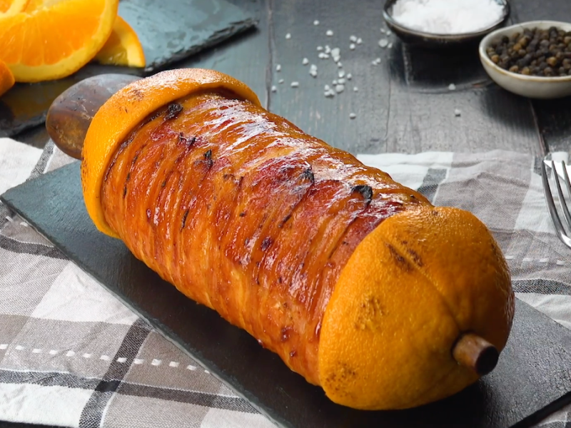 Ein Cordon bleu am Spieß vom Grill auf einer Schieferplatte.