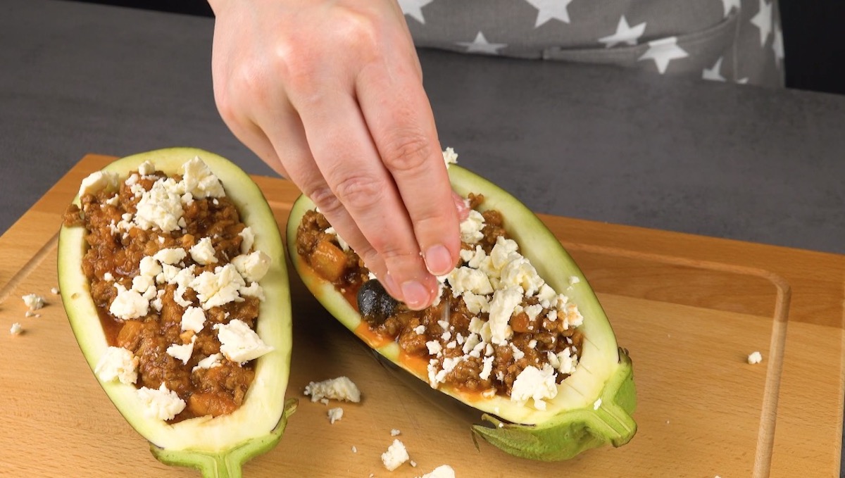 Feta-KÃ¤se wird Ã¼ber 2 mit einer Hackfleisch-Mischung gefÃ¼llten AuberginenhÃ¤lften verteilt. 