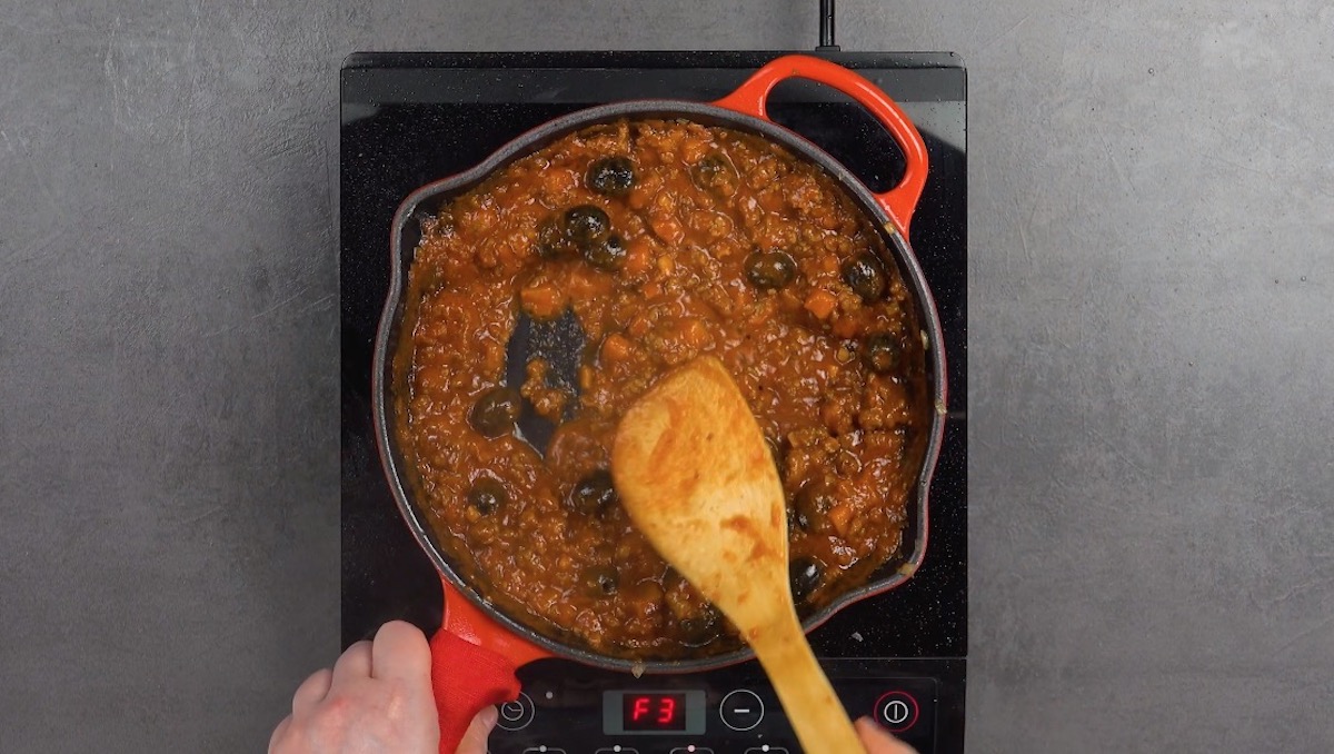 AuberginenwÃ¼rfel werden mit Oliven, passierten tomaten und Hackfleisch in Pfanne angebraten. 