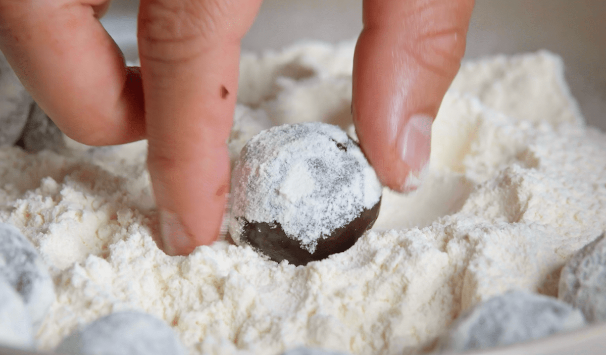 Brigadeiros werden mit Fingern geformt und in Mehl gewendet