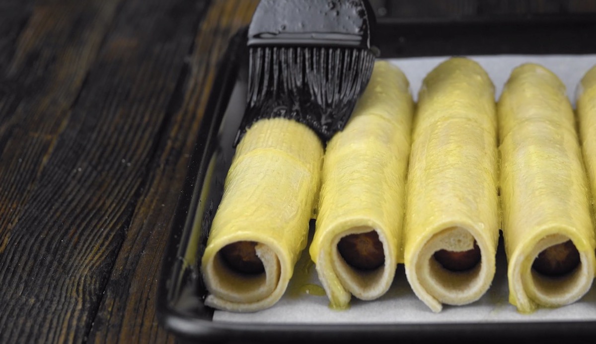 Die ToastrÃ¶llchen auf dem Backblech werden mit flÃ¼ssiger Butter bepinselt