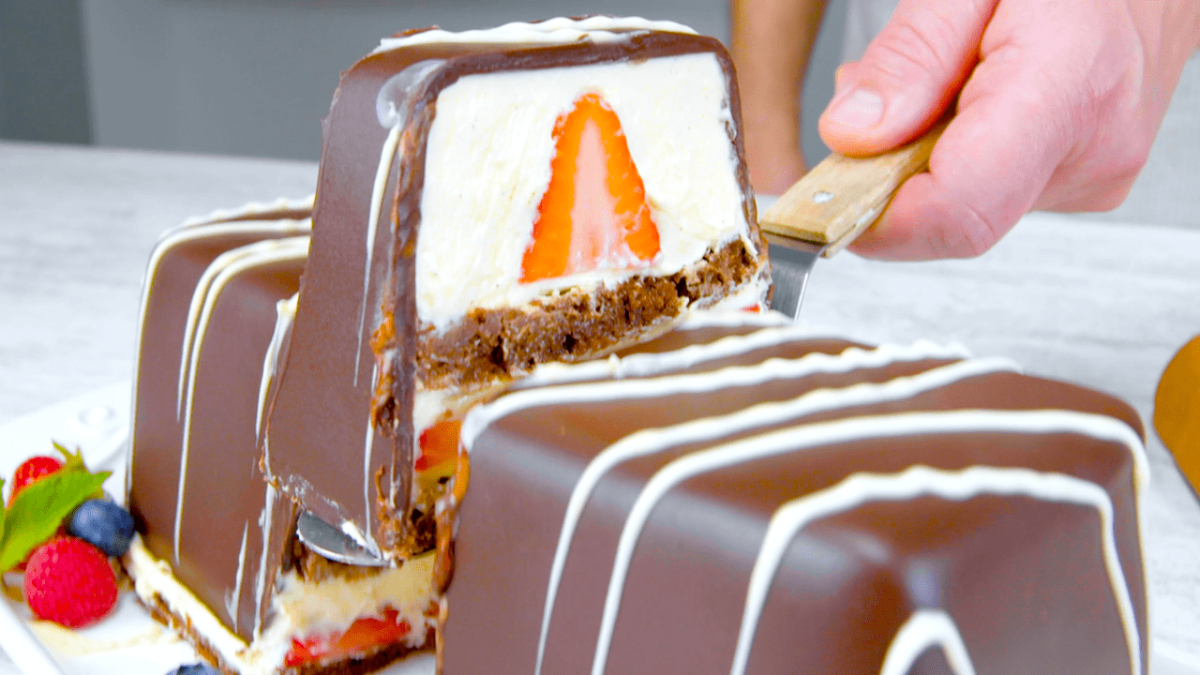 Schoko-Dessert mit Vanillecreme und Erdbeeren, aus dem ein Stück geschnitten wird.