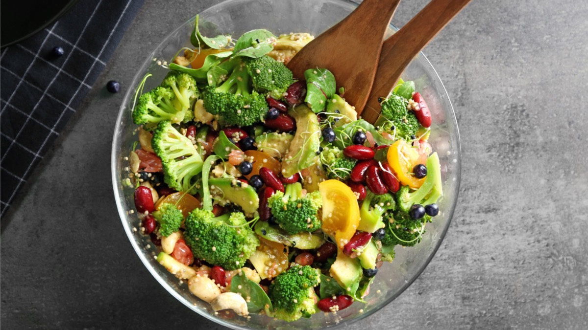 Eine Schüssel Brokkolisalat mit Salatbesteck aus Holz.