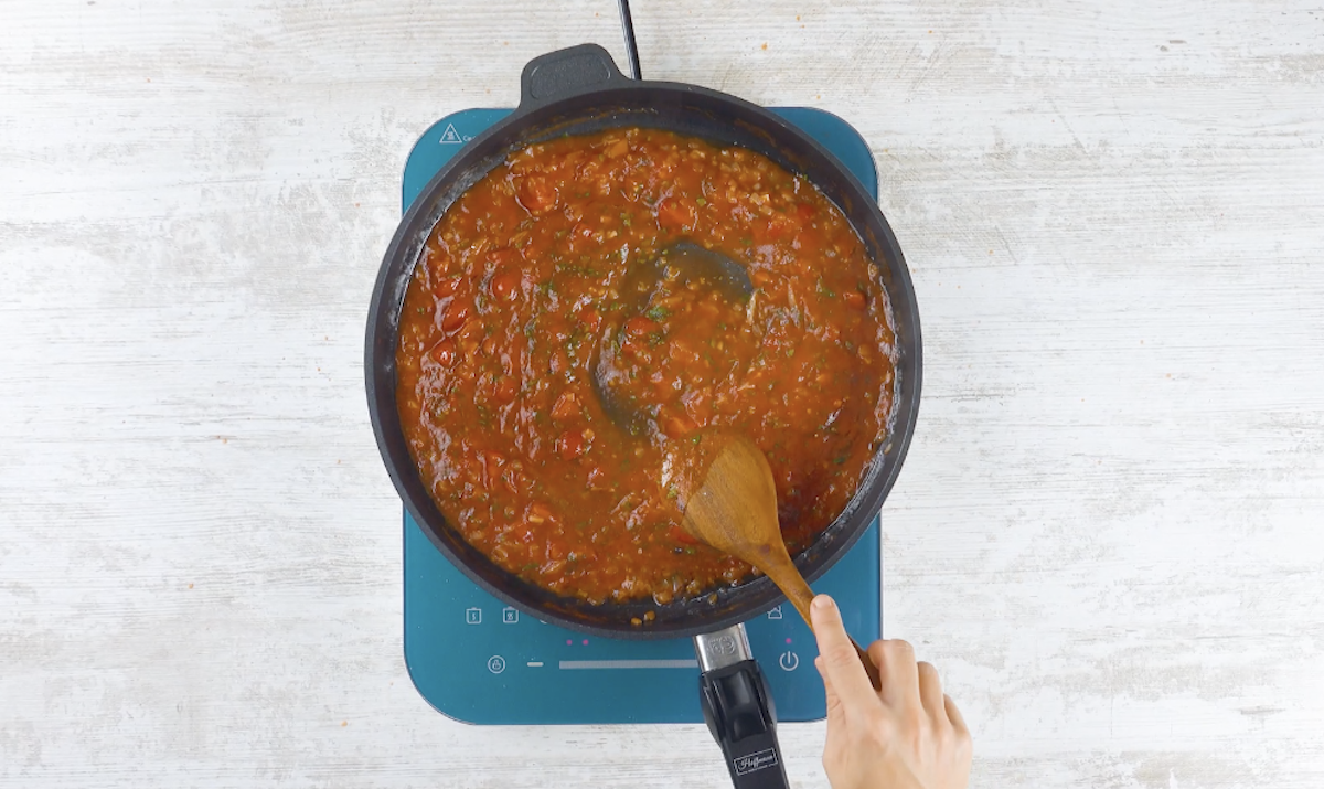 Klein geschnittene Zwiebeln werden mit gehackten Tomaten in Pfanne abgelÃ¶scht