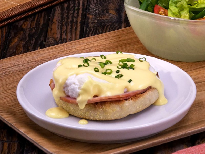 Ein Ei Benedict auf einem halbierten Toastbrötchen mit Kasseler und Sauce Holondaise.