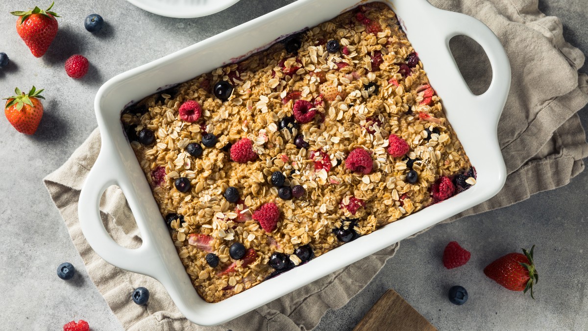 Ein Haferflocken-Auflauf mit Beeren von oben fotografiert. Daneben liegen Beeren und weitere Zutaten.