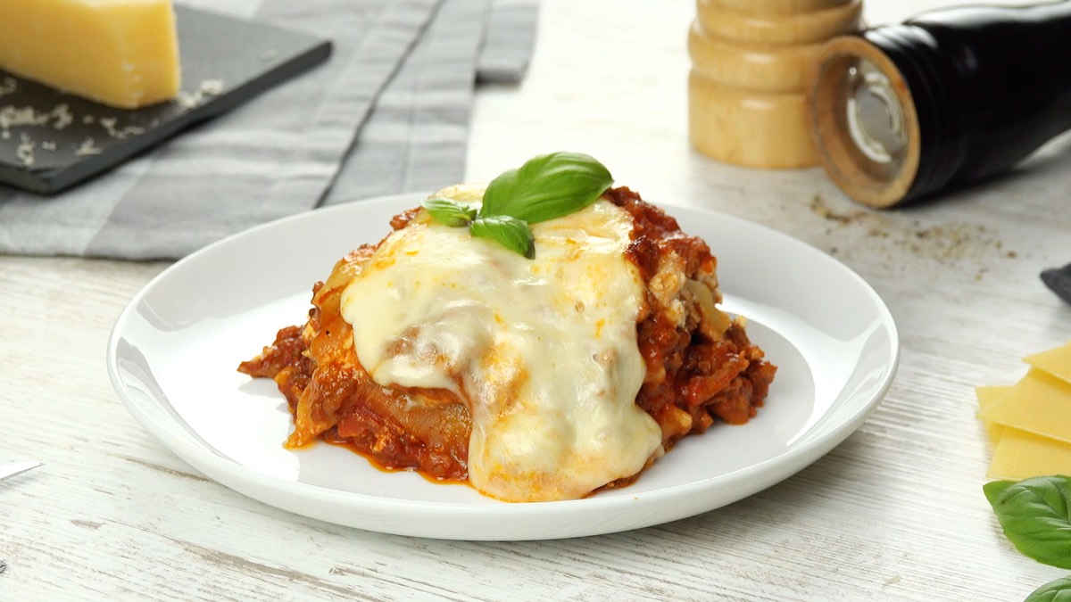 Eine Portion One-Pot-Lasagne auf einem Teller, im Hintergrund Pfeffer- und Salzmühle.