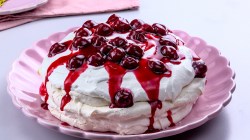 Rosa Teller mit Pavlova mit Kirschen