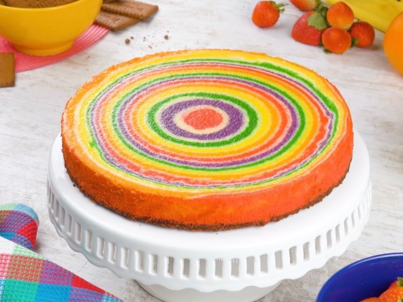 Ein Regenbogen-Fruchtkuchen auf einer Kuchenplatte.