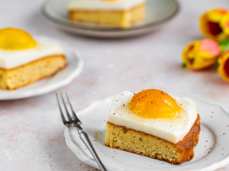 Heller Tisch mit drei Tellern und je einem Stück Spiegeleikuchen