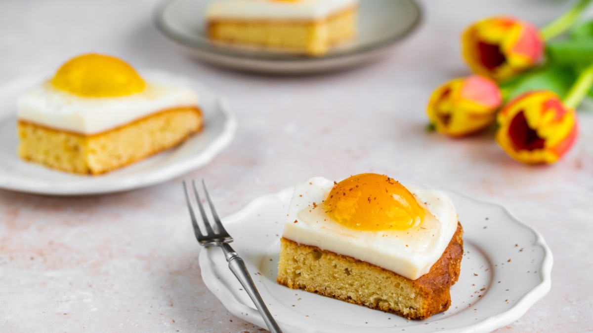 Heller Tisch mit drei Tellern und je einem Stück Spiegeleikuchen