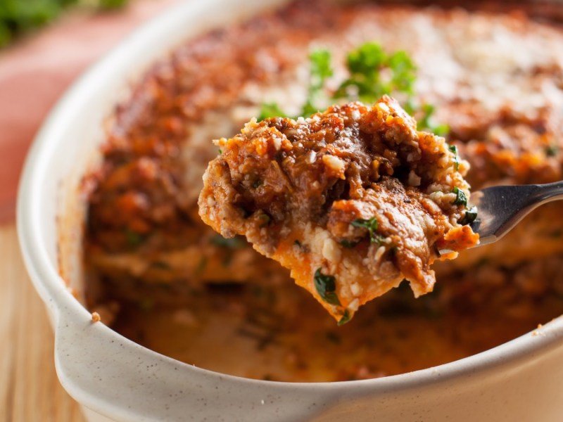 Eine Portion Süßkartoffel-Lasagne wird mit einer Gabel aus der auflauffrom entnommen.