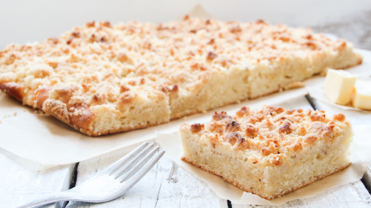 Ein StÃ¼ck Butter-Streuselkuchen vom Blech vor dem ganzen Kuchen