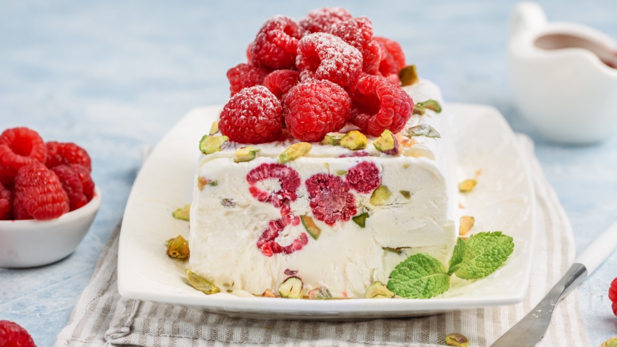 Angeschnittenes Himbeer-Semifreddo mit Pistazien auf Teller