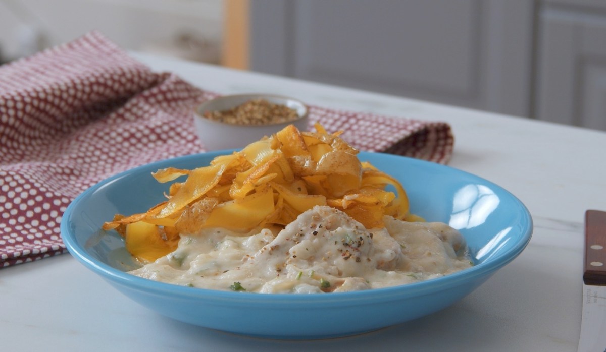 Schweinefilet in Blumenkohlsoße mit Kartoffelnudeln, serviert auf einem blauen Teller.