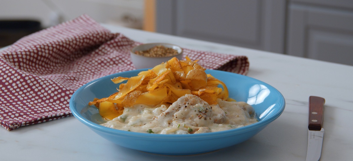 Schweinefilet in Blumenkohlsoße mit Kartoffelnudeln, serviert auf einem blauen Teller.