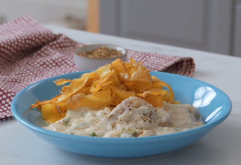 Schweinefilet in Blumenkohlsoße mit Kartoffelnudeln, serviert auf einem blauen Teller.