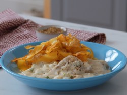 Schweinefilet in Blumenkohlsoße mit Kartoffelnudeln, serviert auf einem blauen Teller.