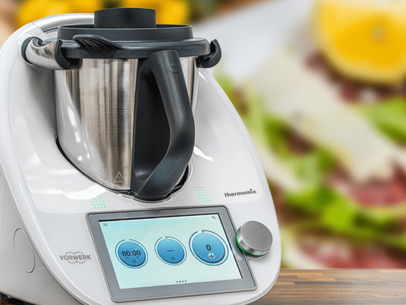 Ein Thermomix, im Hintergrund Lebensmittel