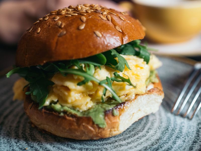 Frühstücksburger mit Rührei und Rucola, serviert auf einem Teller.