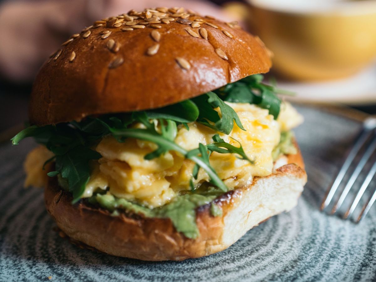 FrÃ¼hstÃ¼cksburger mit RÃ¼hrei und Rucola, serviert auf einem Teller.