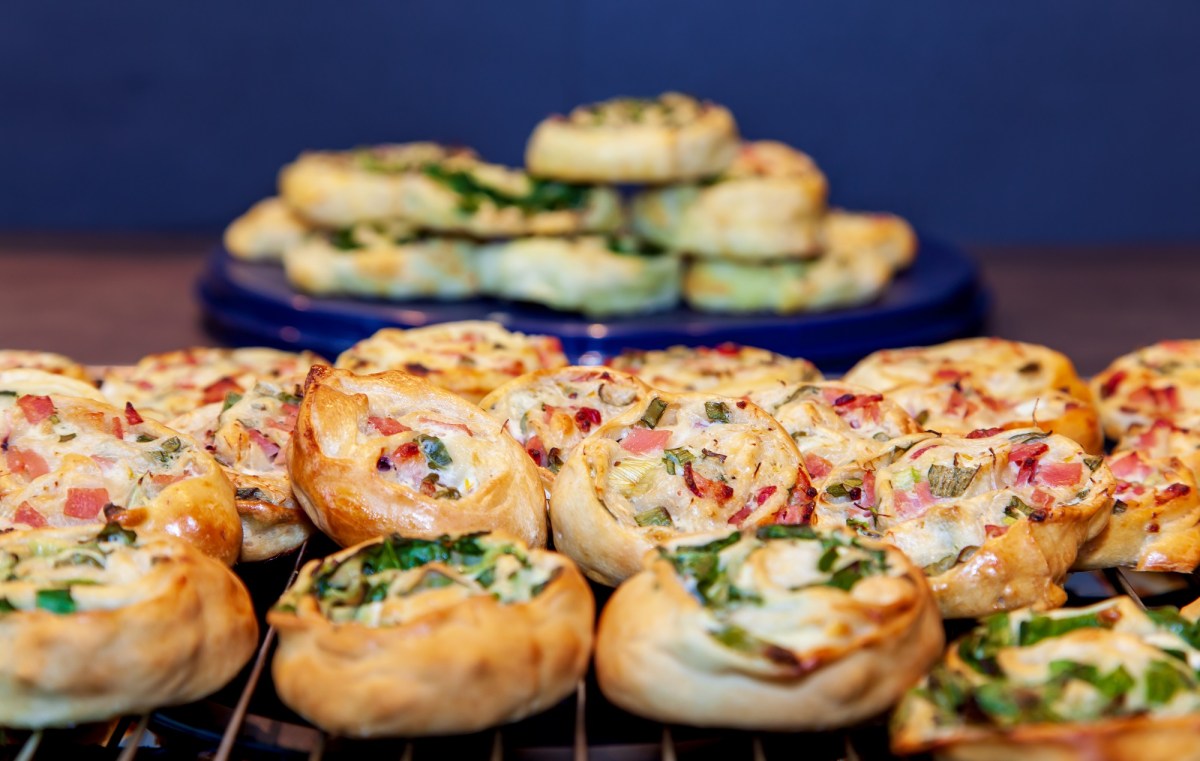 Mehrere Flammkuchen-Schnecken gestapelt auf einem Kuchengitter.