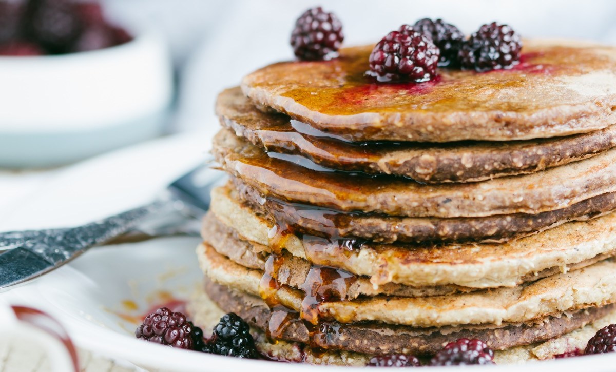 Ein Stapel Haferflocken-Pancakes mit frischen Brombeeren und Sirup.