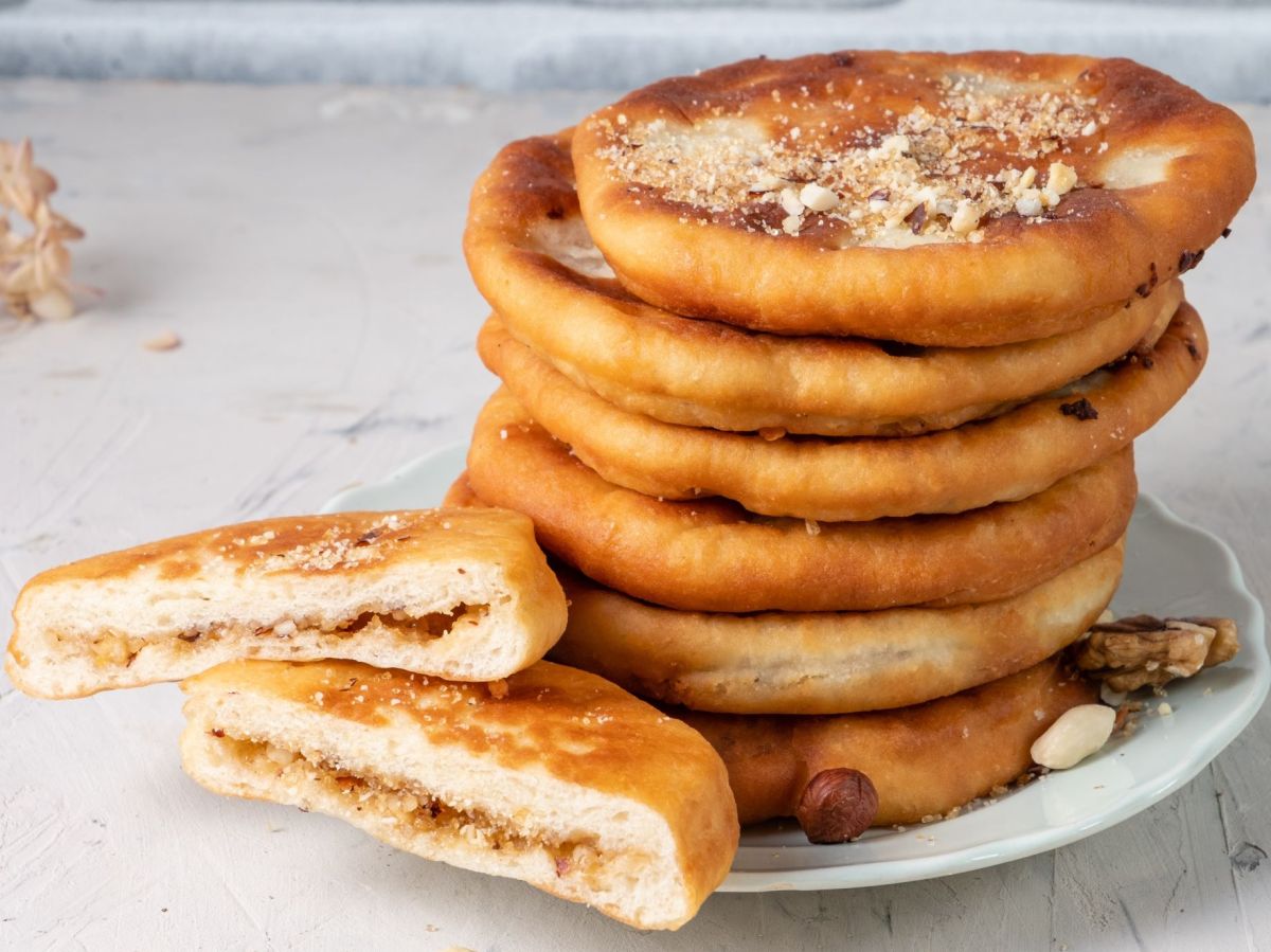 Koreanische Pfannkuchen auf einem Teller gestapelt, dekoriert mit Nüssen. Ein Pfannkuchen liegt angeschnitten in zwei Hälften auf dem Teller.