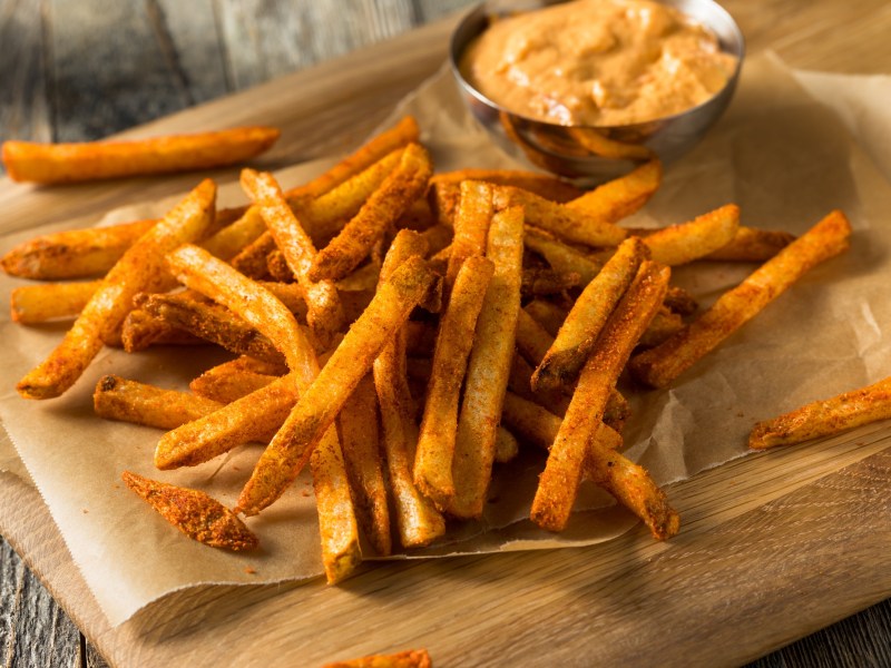 Masala-Fritten auf einem holzbrett mit Limetten-Mayo