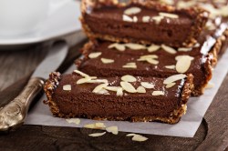 No-Bake-Schokoladentarte, bestreut mit Mandeln, in Stücke geschnitten auf einem Backpapier