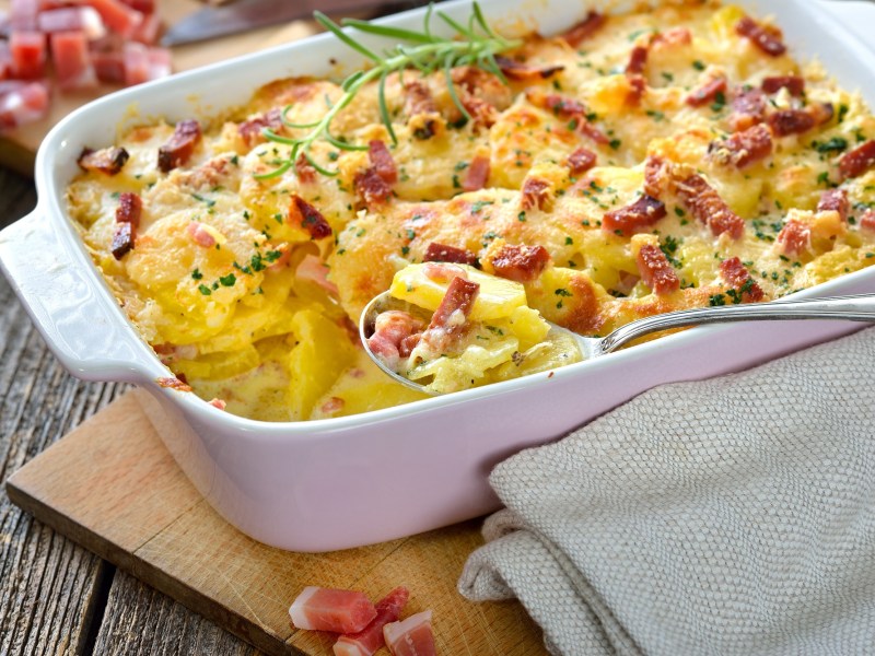 Carbonara-Kartoffelauflauf mit Speck in einer Auflaufform, Nahaufnahme.