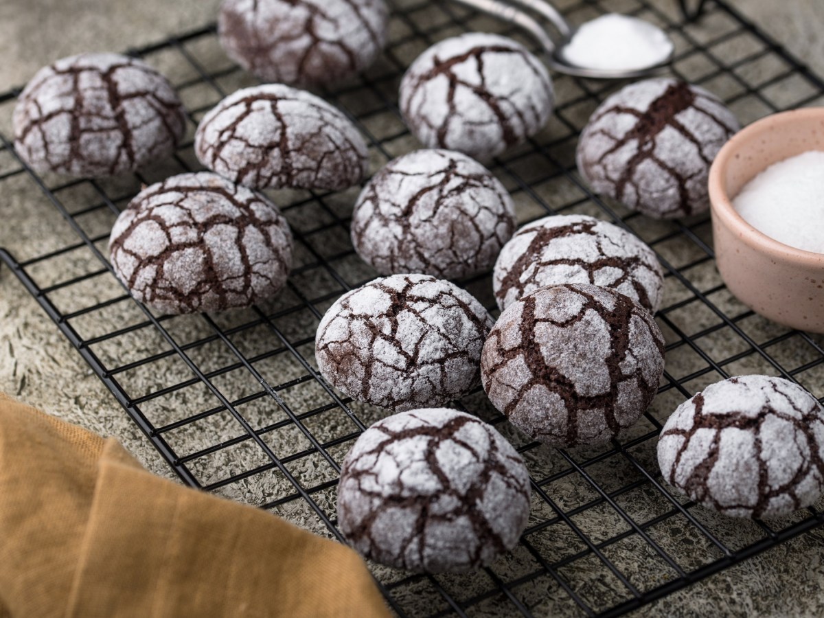 Chocolate Crinkle Cookies auf einem Backgitter mit Puderzucker