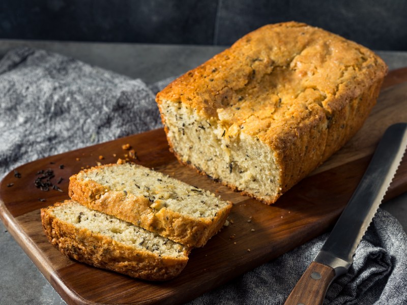 Holzbrett mit einem Earl grey Kastenkuchen und zwei abgeschnittenen Scheiben Kuchen.