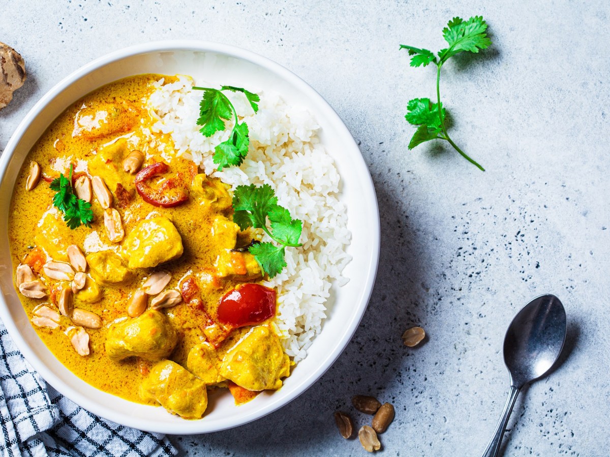 Schüssel mit Reis und Erdnuss-Curry auf einem Tisch.