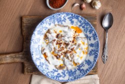 türkische Pasta mit Hackfleisch auf einem blau gemusterten Teller mit Joghurtsoße und Paprika-Butter