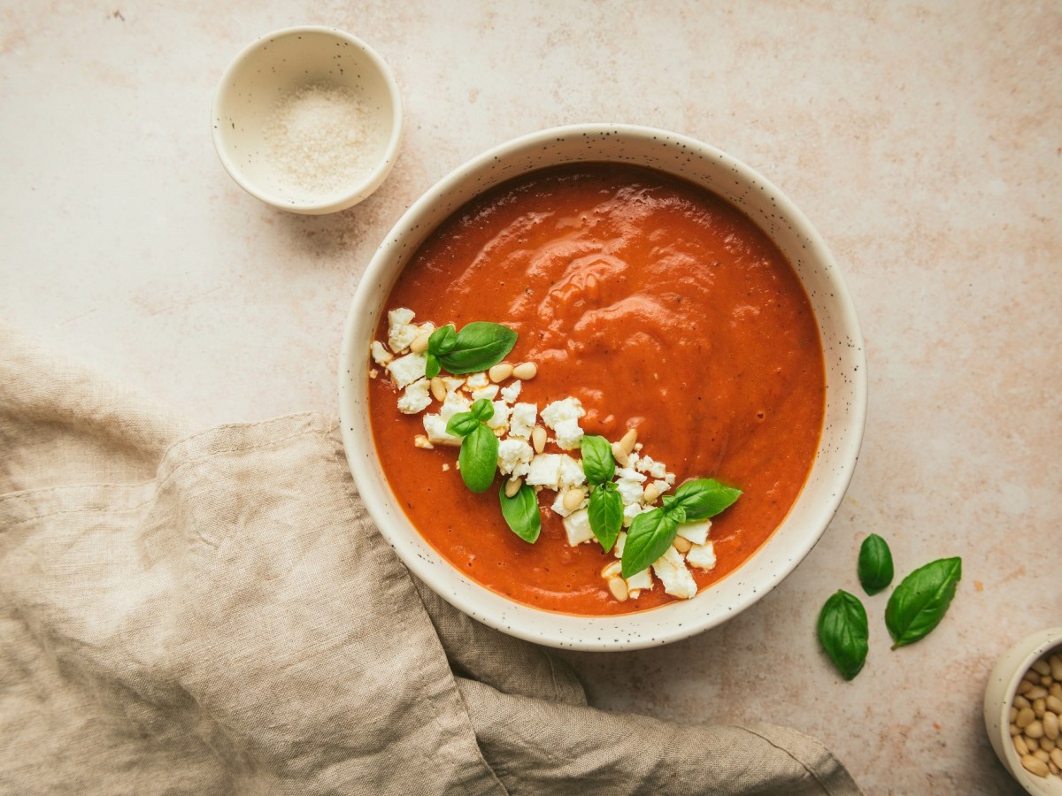 Griechische Tomatensuppe mit Feta in einer Schüssel, garniert mit Feta, Pinienkernen und Basilikum, Draufsicht.