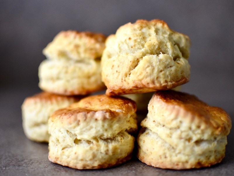 Klassische Scones übereinandergestapelt auf einem dunklen Untergrund.