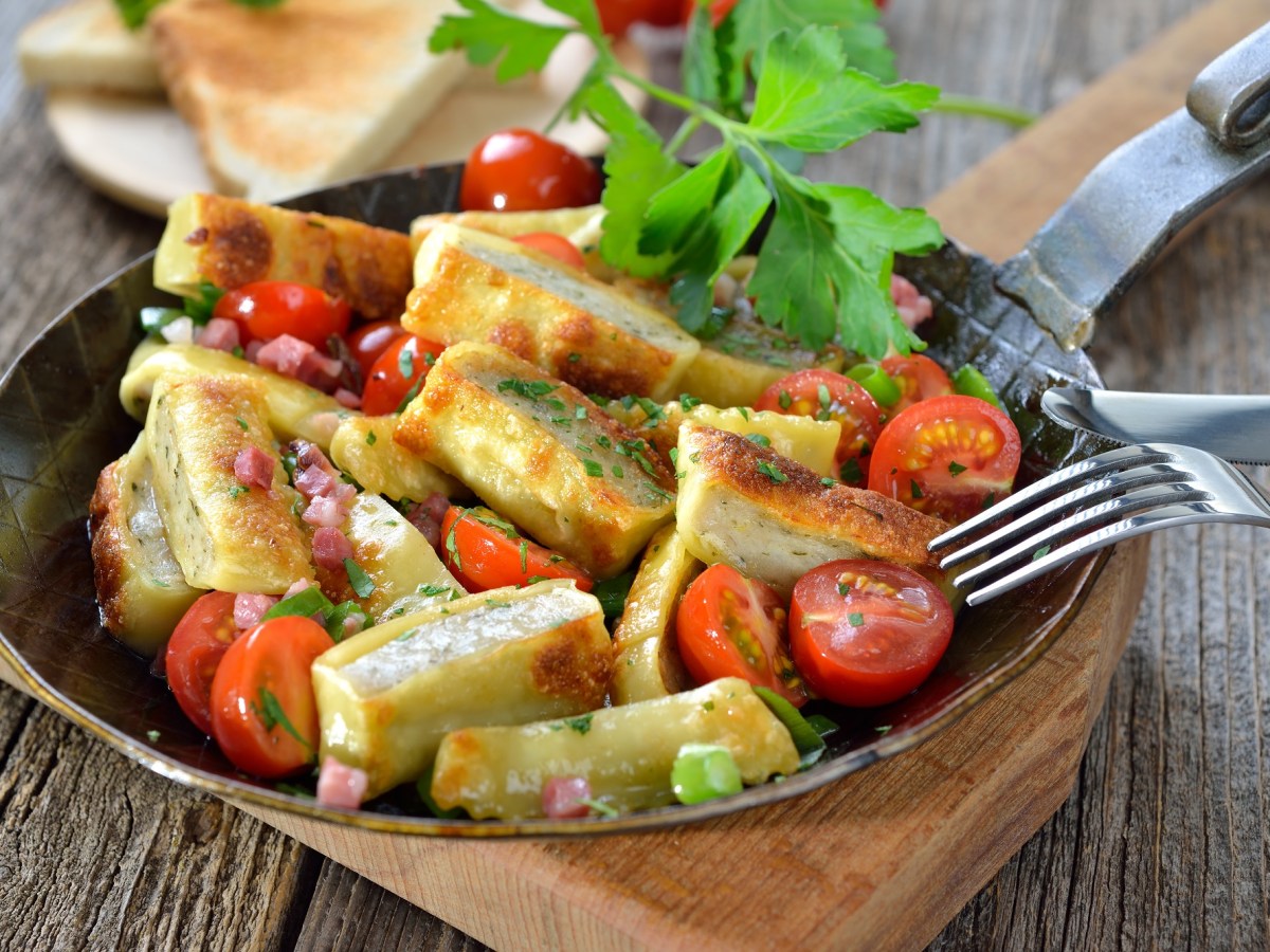 Pfanne mit Maultaschen-Pfanne auf einem Holzbrett