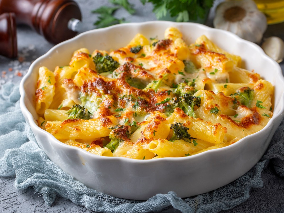 Nudelauflauf mit Brokkoli und Gorgonzola in einer weißen Auflaufform auf einem blauen Tuch.