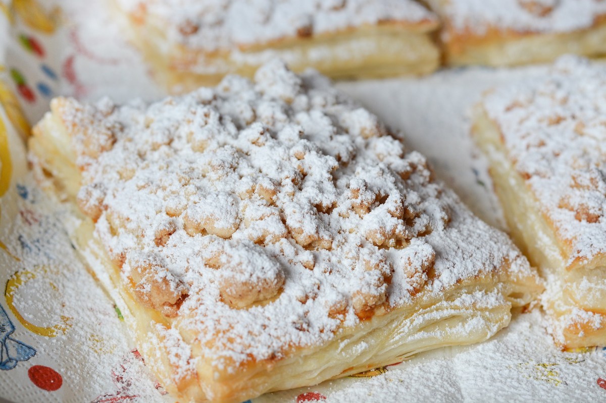 Prasselkuchen-Rezept: Ein Stück Prasselkuchen mit Streuseln und Puderzucker, Nahaufnahme.