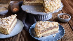 Zwei Stücke schwedische Mandeltorte auf Tellern im Vordergrund. Dahinter die restliche Torte auf einer Kuchenplatte.