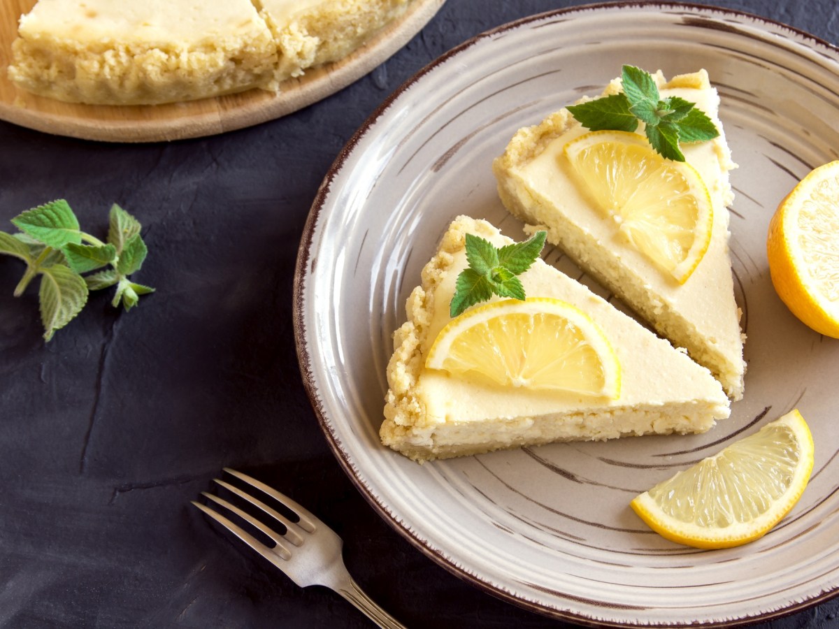 Teller mit zwei StÃ¼cken Zitronen-Cheesecake auf dunklem Untergrund